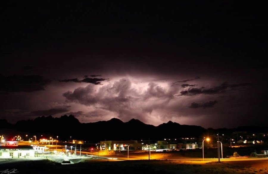 Lightning-lit storm clouds over the Organ Mountains and Las Cruces at night